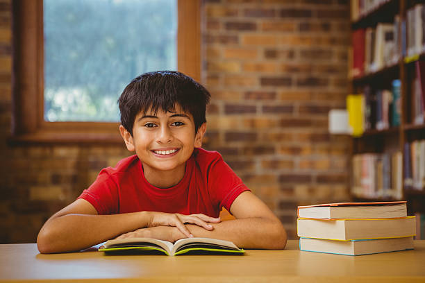 Portrait of cute little boy reading book in the library